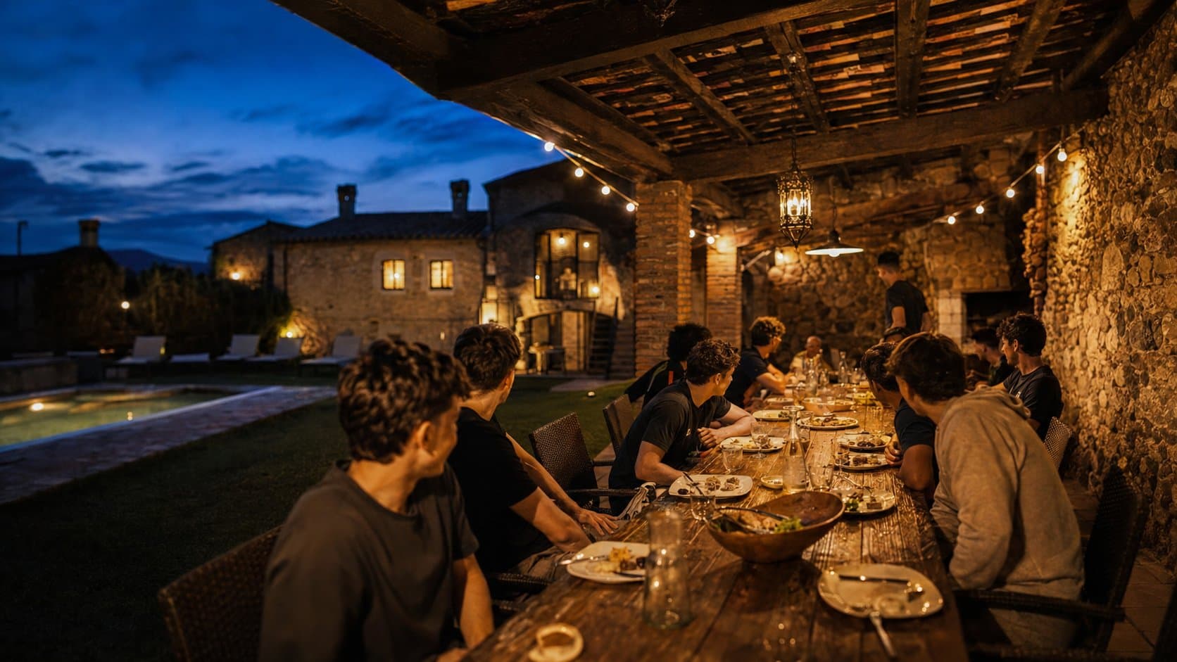 Team beim Abendessen an einer langen Tafel auf der Finca-Terrasse zur blauen Stunde